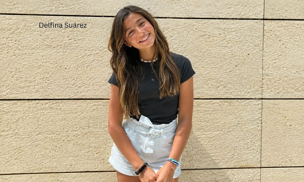 Delfina Suárez smiling in a casual outfit while standing against a beige stone wall.