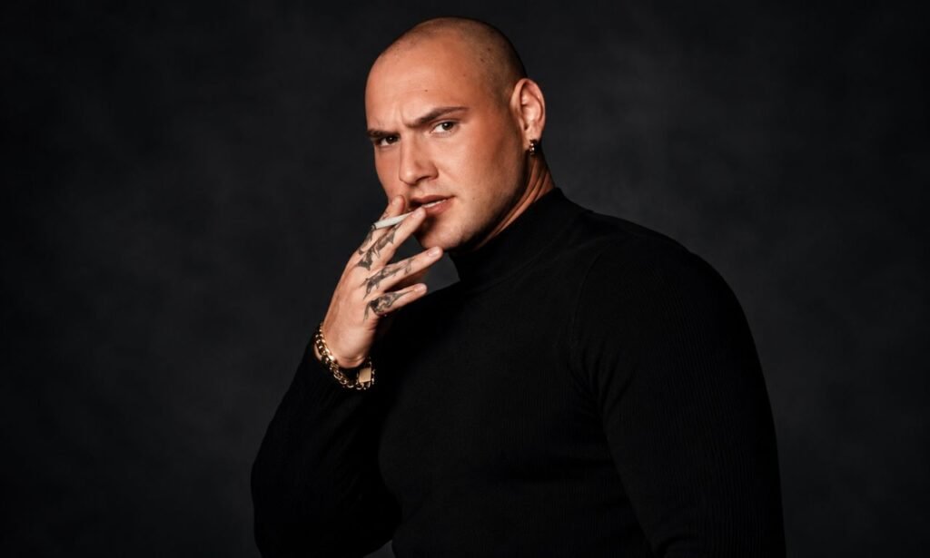 eo Skepi posing in a black turtleneck against a dark background in a cinematic portrait.