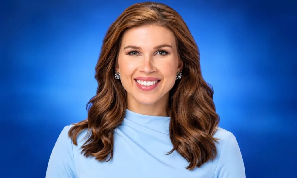 Marisa Woloszyn-style professional meteorologist portrait wearing a light blue blouse against a blue studio background.
